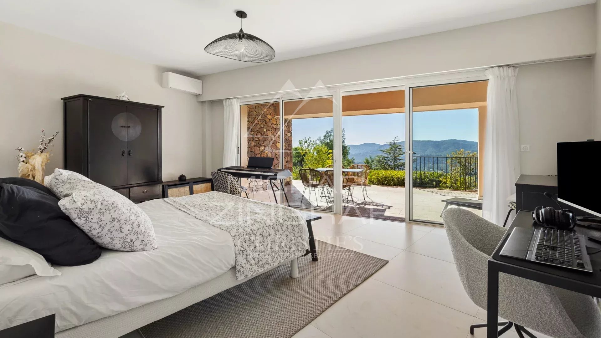 Chambre d'une villa avec vue sur la mer et les collines, accès à une terrasse.