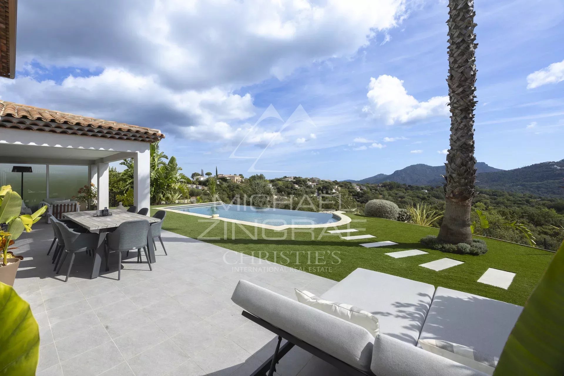 Vue extérieure d'une villa contemporaine avec piscine et jardin, entourée de collines à Mandelieu-la-Napoule.