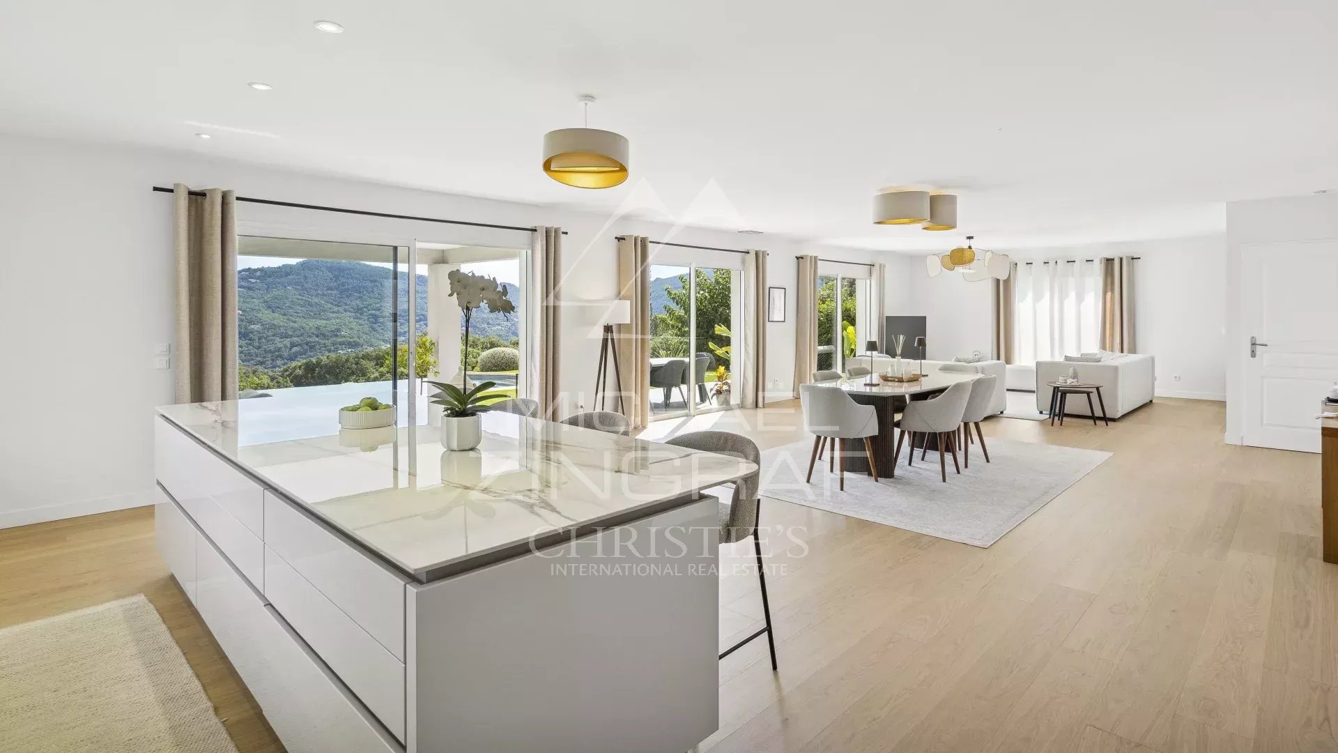 Intérieur d'une villa contemporaine avec vue sur les collines de l'Estérel, salon lumineux et espace repas.