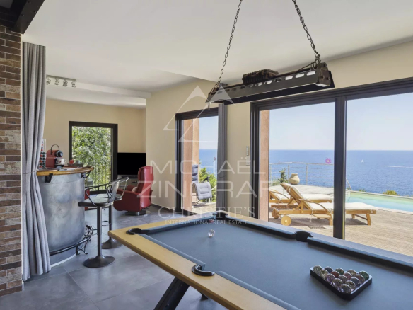 Intérieur d'une propriété rénovée avec vue mer, billard et accès à une terrasse.