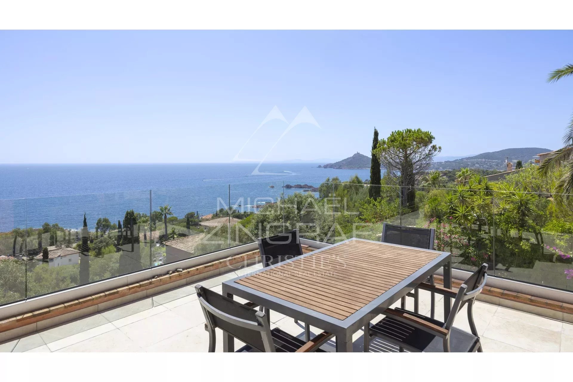 Terrasse avec vue mer à Anthéor, mobilier de jardin en bois, paysage côtier en arrière-plan.