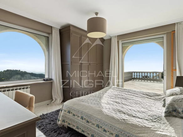 Chambre d'une villa avec vue sur la mer, fenêtres ouvertes sur un balcon.