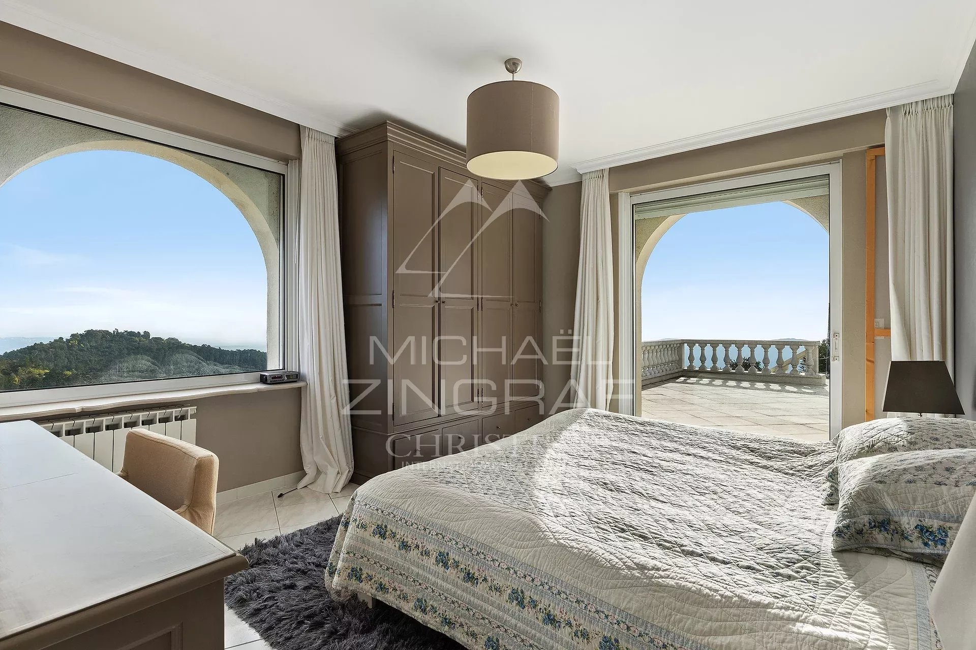 Chambre de villa avec vue panoramique Chambre d'une villa avec vue sur la mer, fenêtres ouvertes sur un balcon.