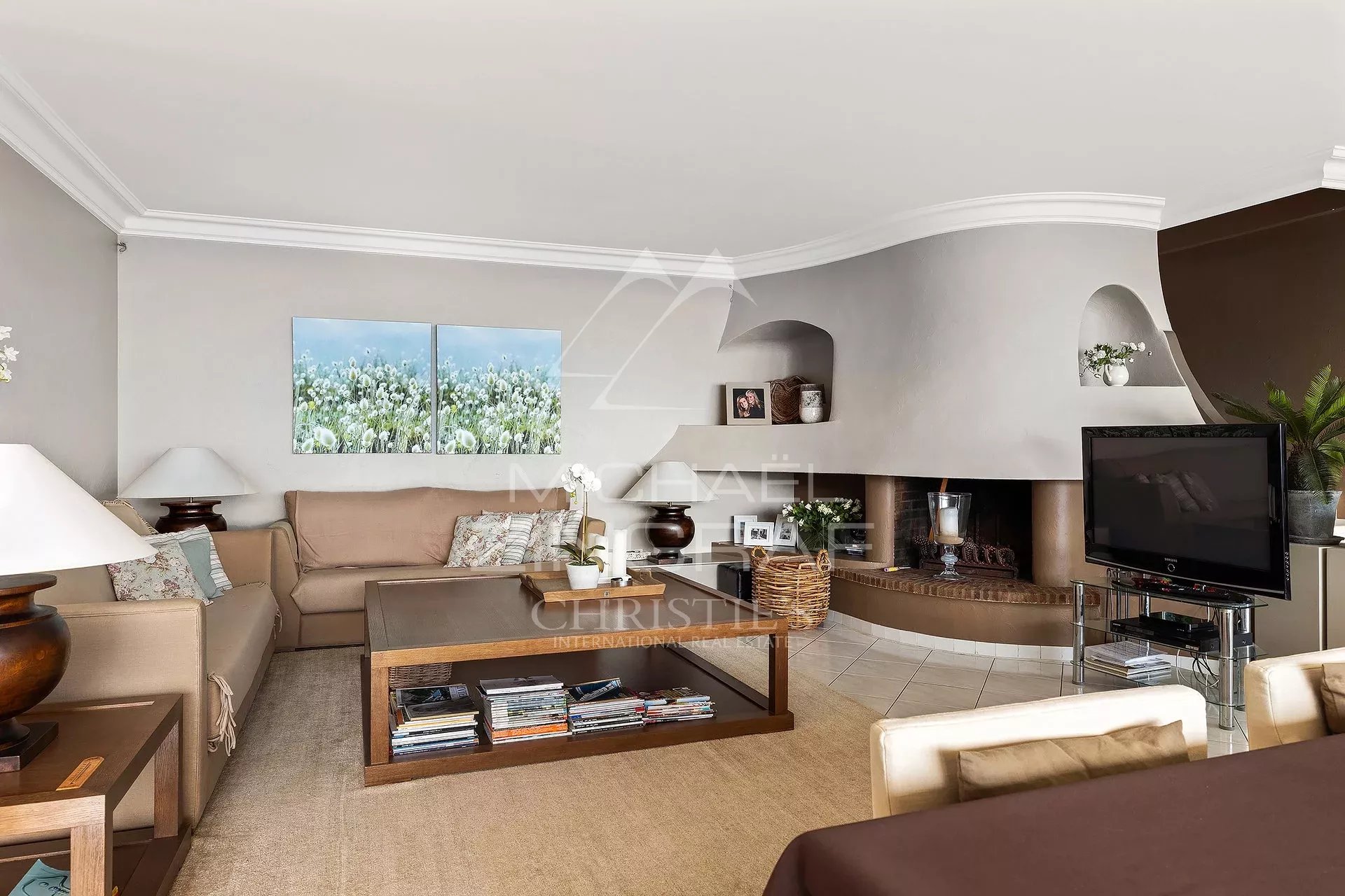 Salon d’une villa à Mandelieu-la-Napoule Intérieur d'une villa avec un salon lumineux et cheminée, décoré avec des tableaux.