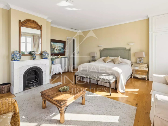 Chambre élégante dans une villa Belle Époque à Mandelieu-la-Napoule, avec cheminée et mobilier raffiné.
