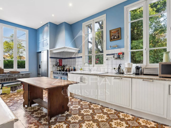 Cuisine spacieuse avec fenêtres et carrelage rétro dans une villa Belle Époque à Mandelieu-la-Napoule.