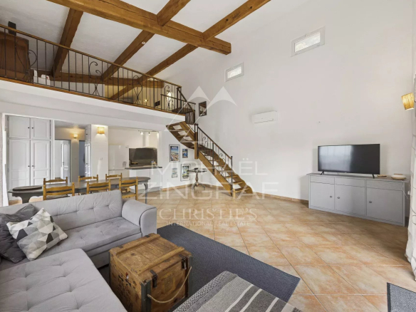 Intérieur d'une maison rénovée avec salon lumineux, cheminée et mezzanine.