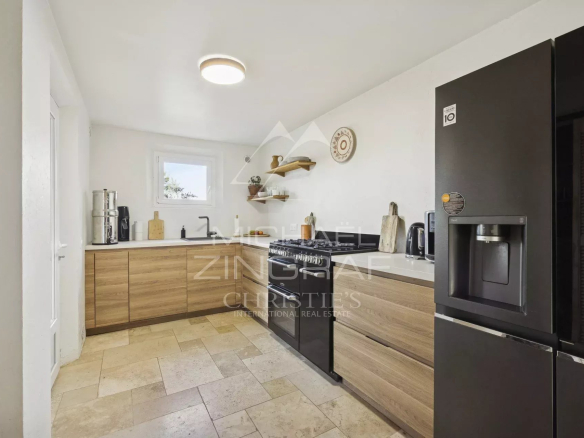 Cuisine moderne avec meubles en bois et appareils électroménagers en noir dans une maison à Mandelieu-la-Napoule.