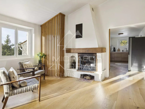 Intérieur d'une maison avec salon lumineux, cheminée et parquet en bois.