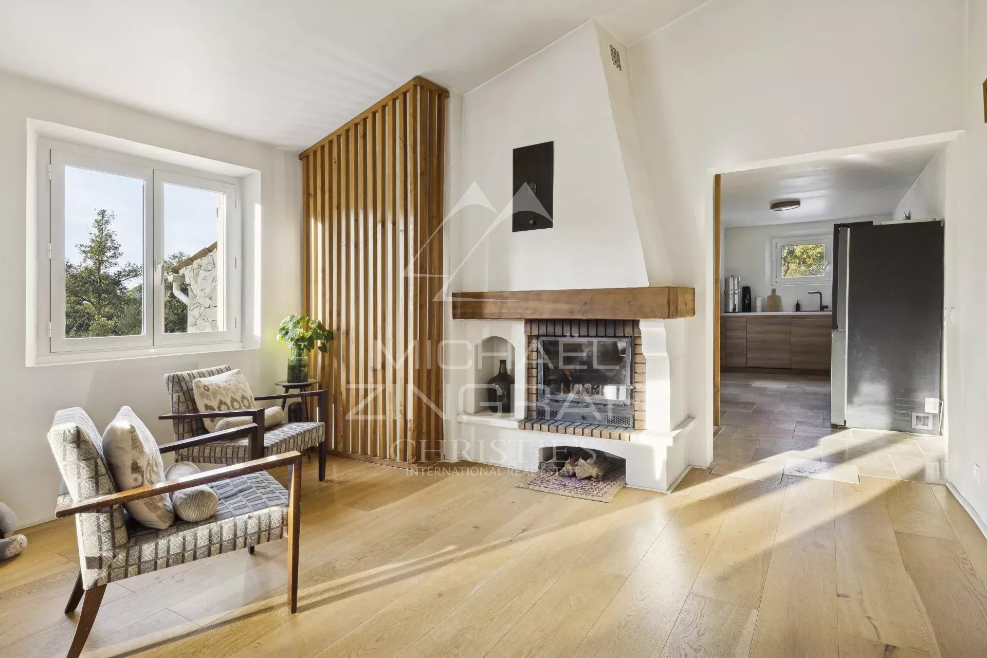 Intérieur d'une maison avec salon lumineux, cheminée et parquet en bois.