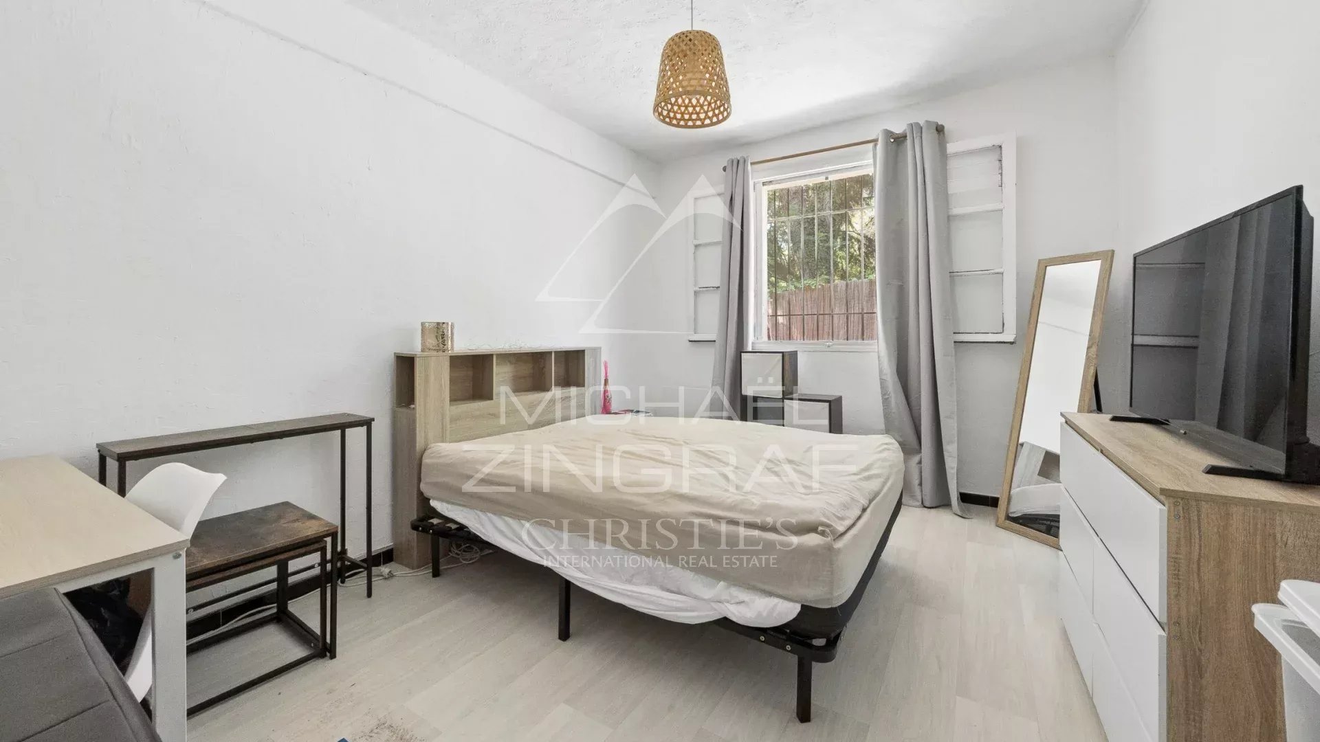 Villa room in need of renovation Room in a villa to be renovated with bed, desk and window, Mandelieu-la-Napoule.