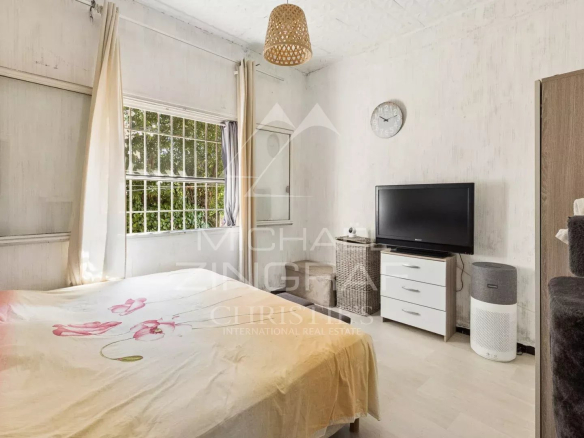 Room in a villa to be renovated with bed, television and window overlooking the outside.