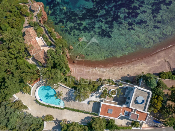 Vue aérienne d'une villa pieds dans l'eau avec piscine et accès à la mer, entourée de verdure.