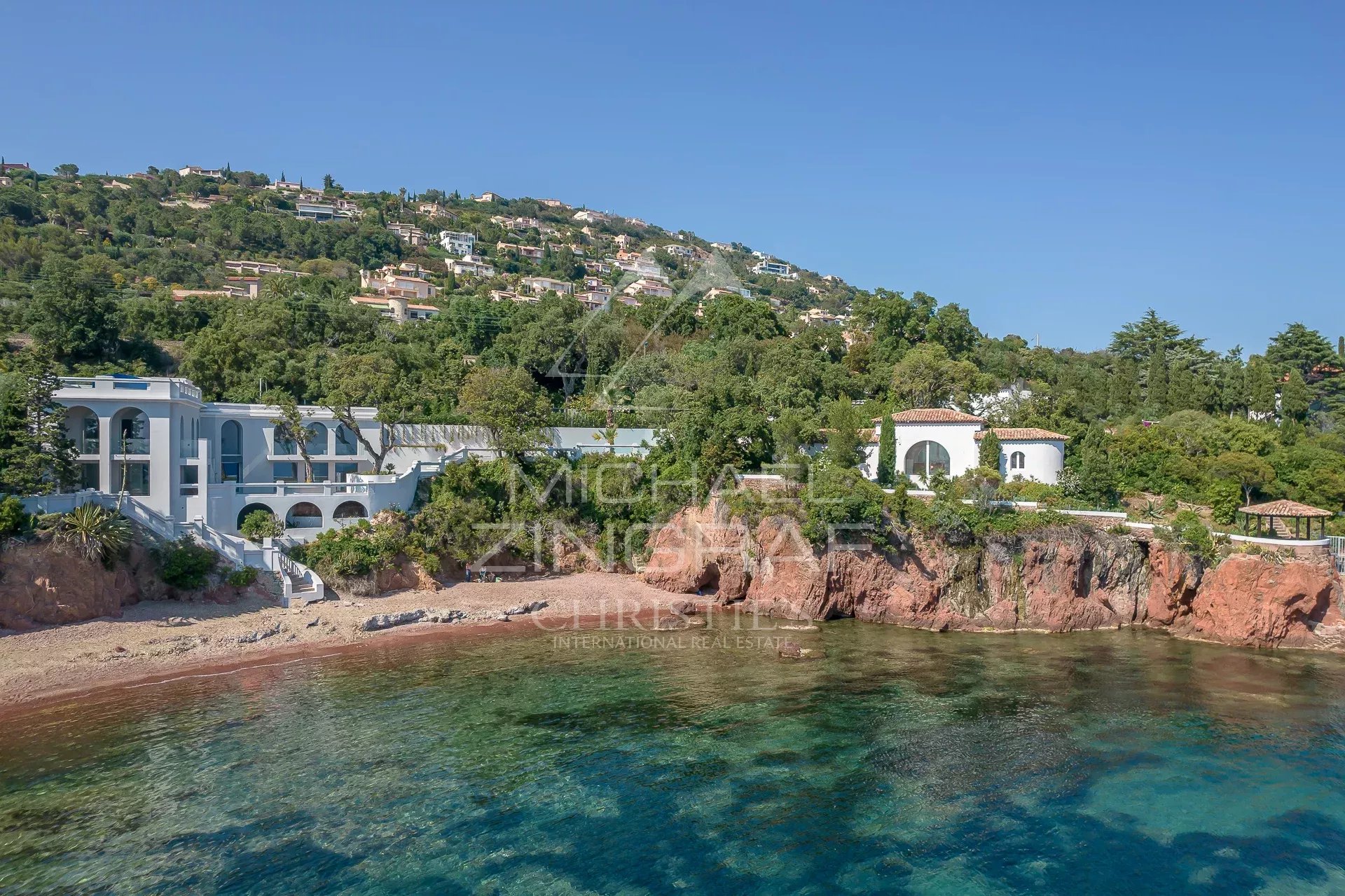 Villa pieds dans l'eau à Saint-Raphaël, entourée de verdure et de rochers, vue sur la mer.