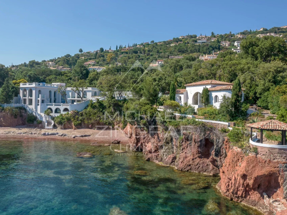 Villa pieds dans l'eau avec piscine, située près de Saint-Raphaël, entourée de verdure et de rochers.