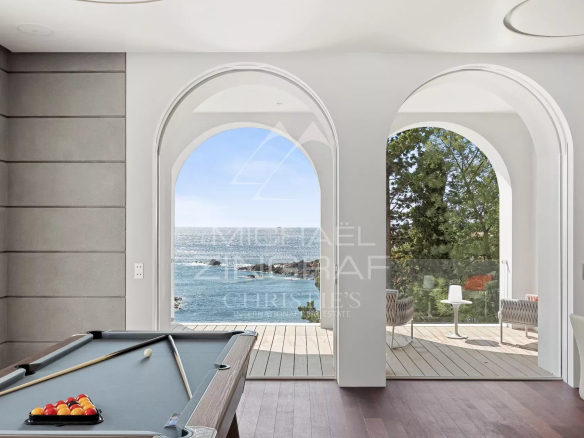 Intérieur d'une villa moderne avec vue sur la mer, piscine et accès extérieur à la plage.