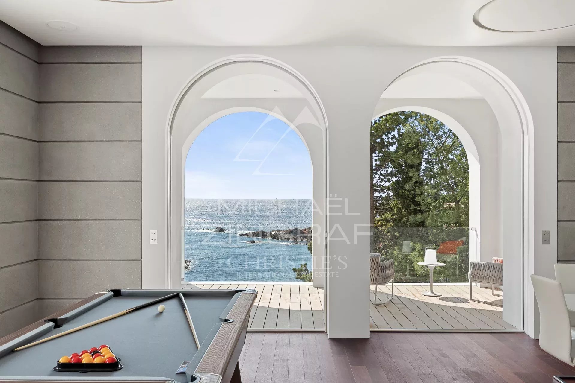 Intérieur d'une villa moderne avec vue sur la mer, piscine et accès extérieur à la plage.
