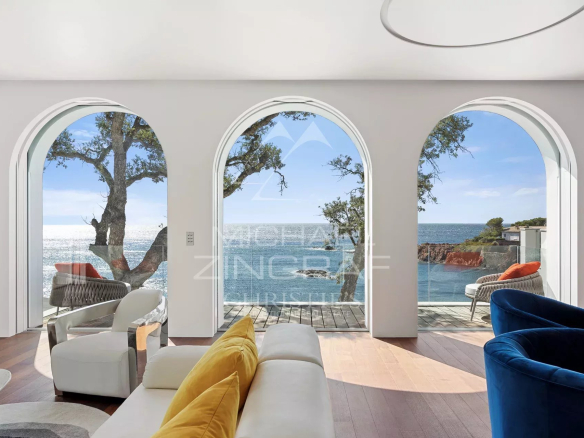 Intérieur d'une villa moderne avec vue sur la mer, fenêtres arrondies et mobilier contemporain.
