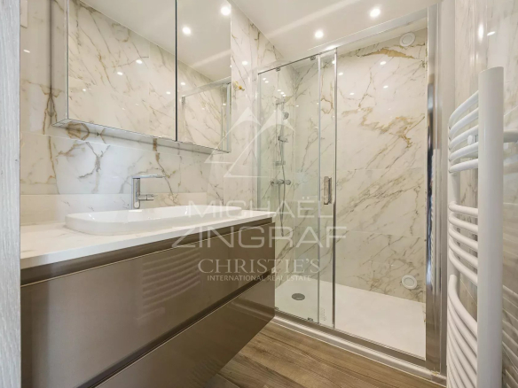 Modern bathroom with glass and marble shower, bright lighting.