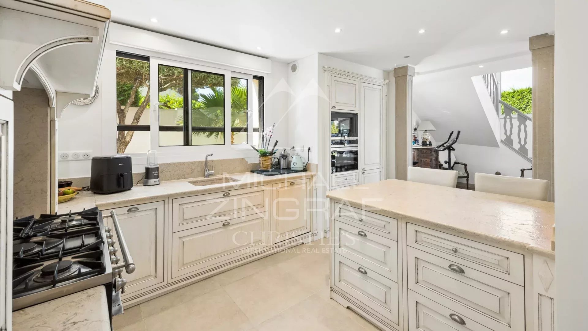 Elegant cuisine in a property in Mandelieu-la-Napoule Interior of a spacious and bright kitchen with white furniture and windows overlooking the outside.