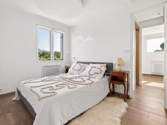 Bright room with bed and window overlooking a garden in Mandelieu-la-Napoule.