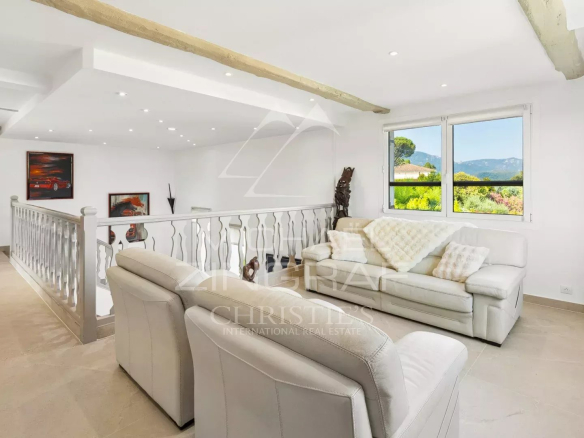 Bright living room with white sofa and garden view in a property in Mandelieu-la-Napoule.
