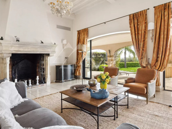 Intérieur d'une villa rénovée à Mandelieu-la-Napoule avec cheminée et mobilier confortable.