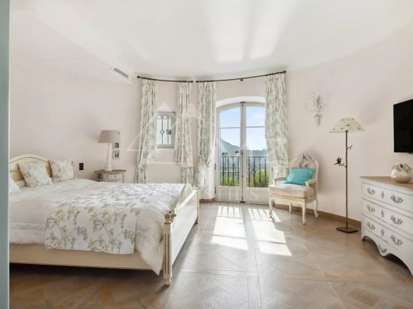 Chambre lumineuse avec vue sur la mer, décorée avec des rideaux clairs et un mobilier élégant.