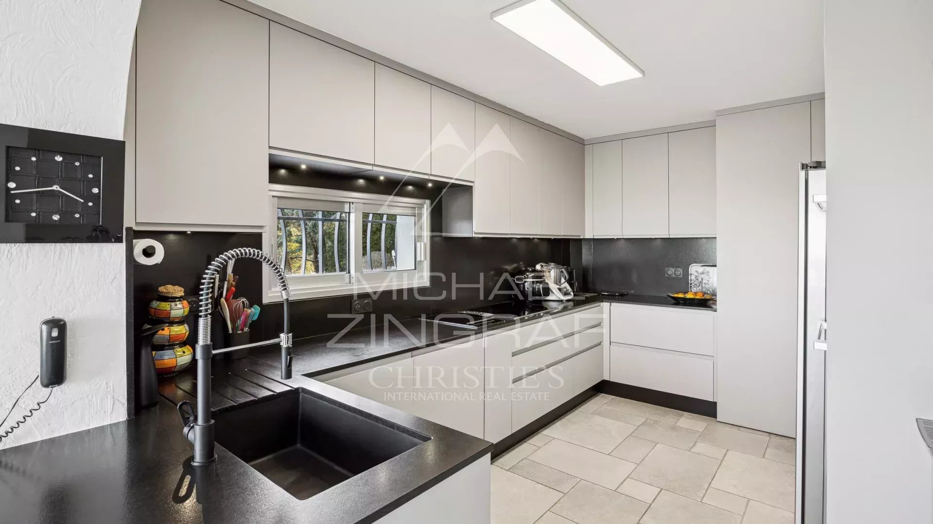 Modern kitchen in a property in Mandelieu-la-Napoule Modern kitchen with black worktops and light-colored furniture, view of the outside.