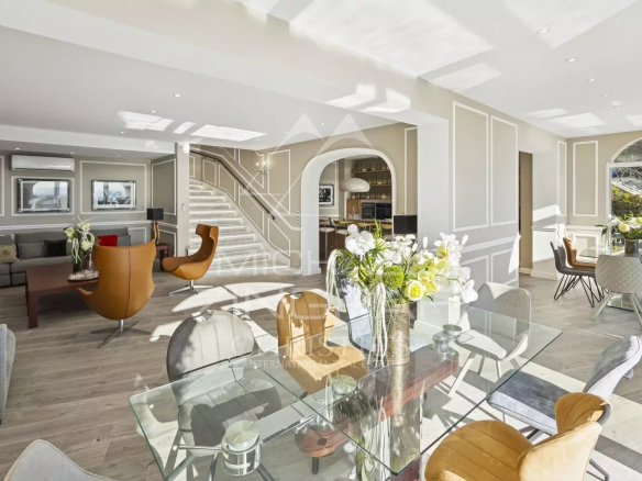 Interior of a renovated villa with living room, dining room and open kitchen, bathed in light.