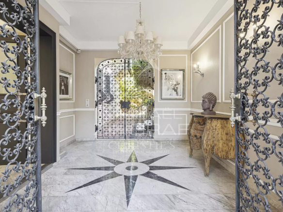 Entrance to a renovated villa with marble flooring and wrought iron doors in Mandelieu-la-Napoule.