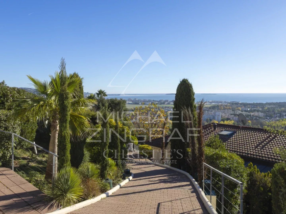 Unobstructed sea view from a hill in Mandelieu-la-Napoule, with palm trees and houses.