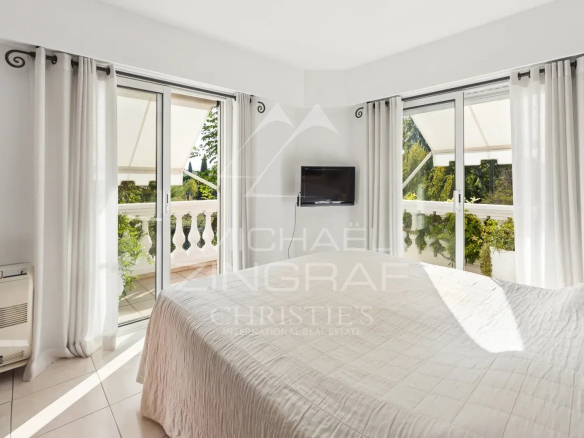 Chambre d'un appartement en duplex à Mandelieu-la-Napoule avec fenêtres donnant sur un balcon.