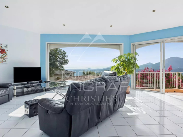 Intérieur d'une villa avec vue sur la mer, salon lumineux et mobilier moderne.