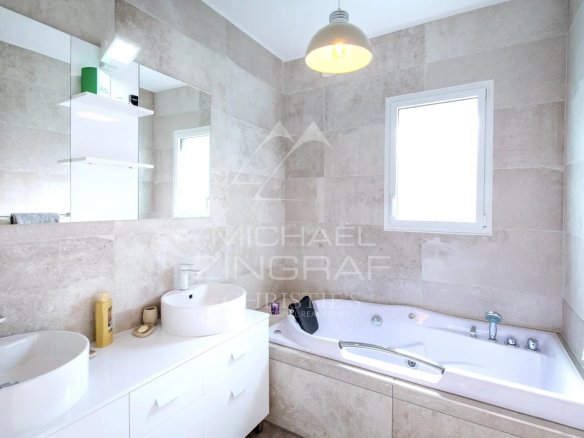 Salle de bain moderne avec baignoire et double vasque dans une propriété contemporaine.