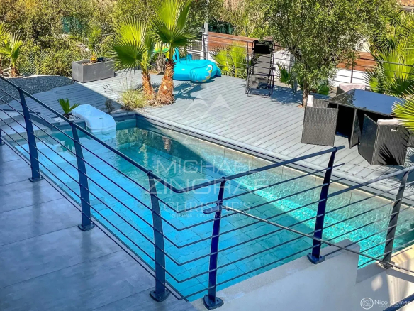 Vue d'une piscine contemporaine entourée de palmiers et d'un espace de vie extérieur à Saint-Raphaël.