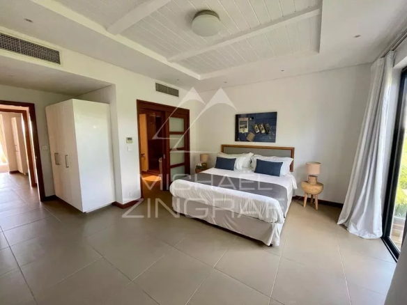 Hotel bedroom with a king bed, two nightstands, blue cushions, artwork above the headboard, wardrobe, and a balcony door to the right.