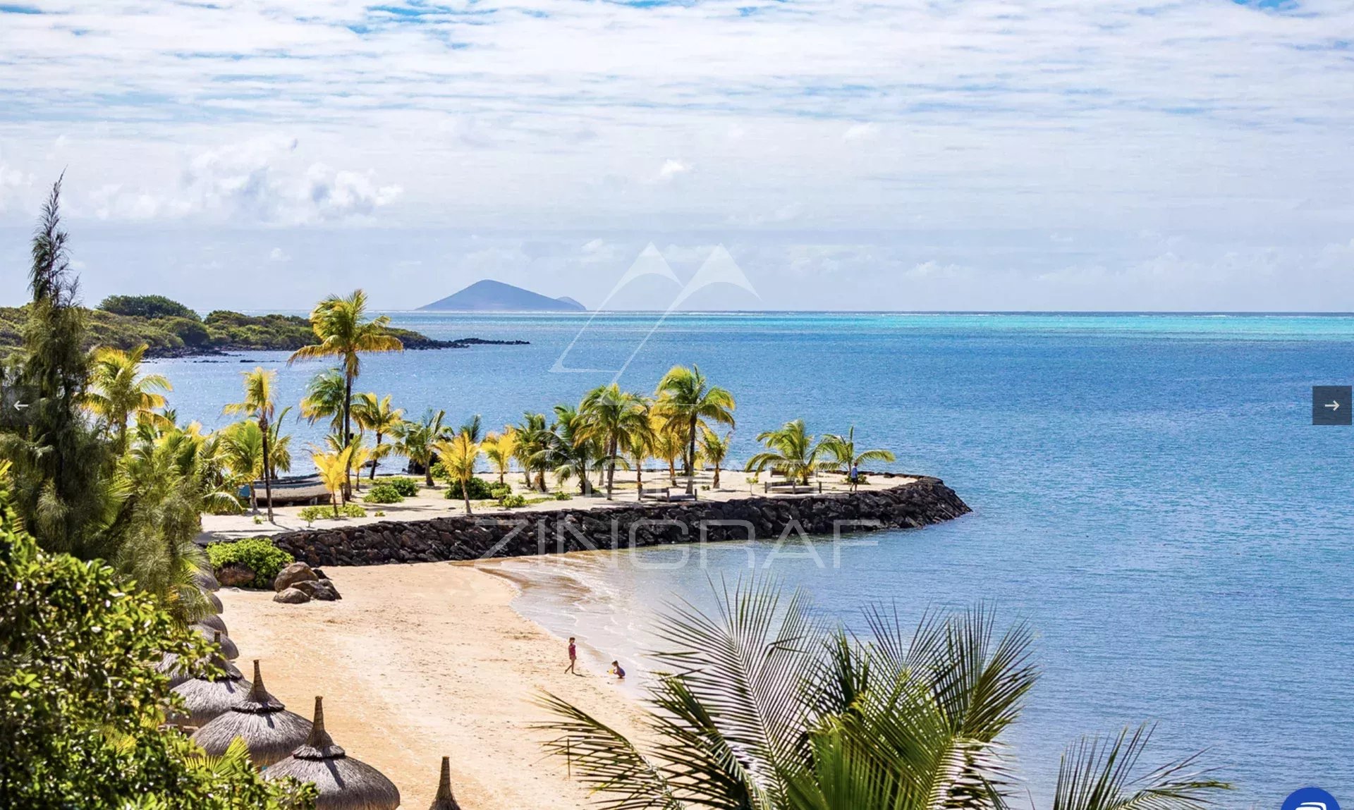 Tropical beach with palm trees, sandy shore, and calm blue water, a small jetty and distant island on the horizon.