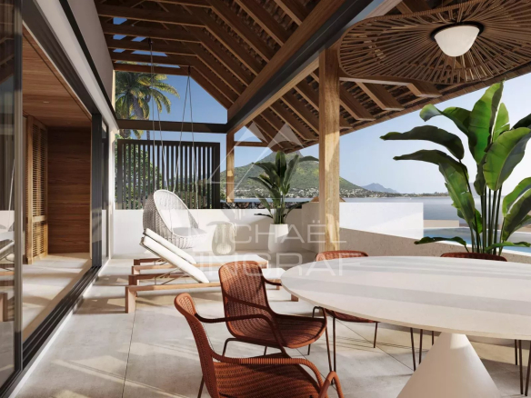 Terrace with white round table and wicker chairs, hanging lounge chair, wooden pergola, and tropical plants overlooking the sea and mountains in the distance.