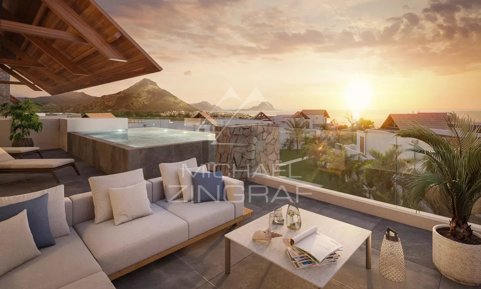 Luxurious outdoor terrace at sunset with a rectangular pool, beige seating, and a glass railing overlooking a tropical coastline and mountains.