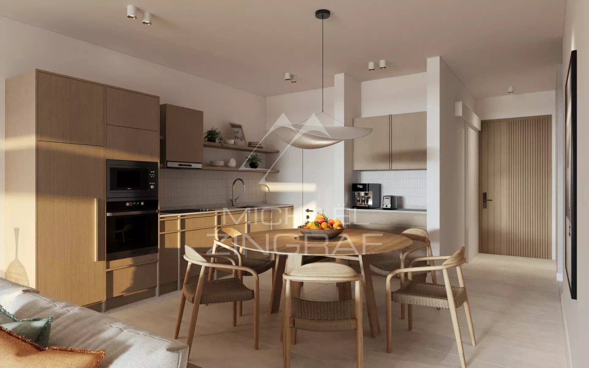 Open-plan kitchen and dining area with wooden cabinets, a round dining table, and six woven chairs; fruit bowl centerpiece. Best for an interior room photo.