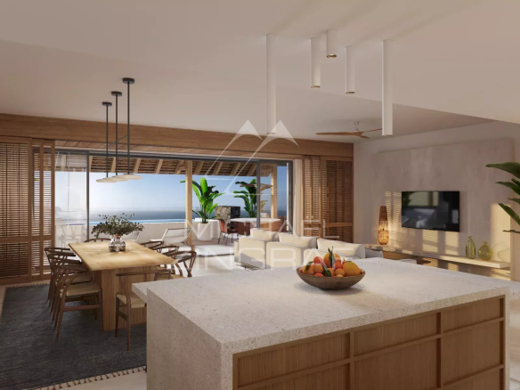 Open-plan kitchen and living area with a stone island, wooden dining table, and sliding glass doors to a balcony overlooking the sea.