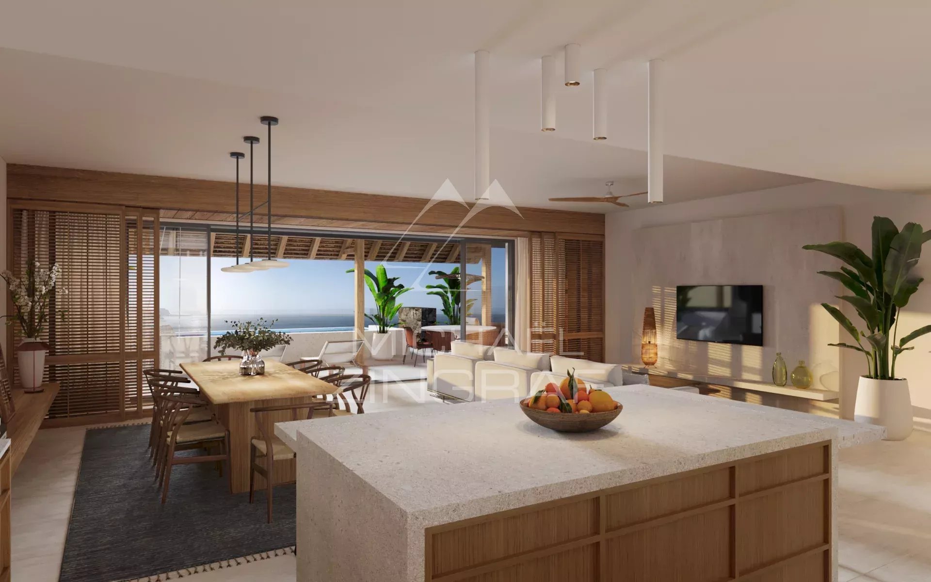 Open-plan kitchen and living area with a stone island, wooden dining table, and sliding glass doors to a balcony overlooking the sea.