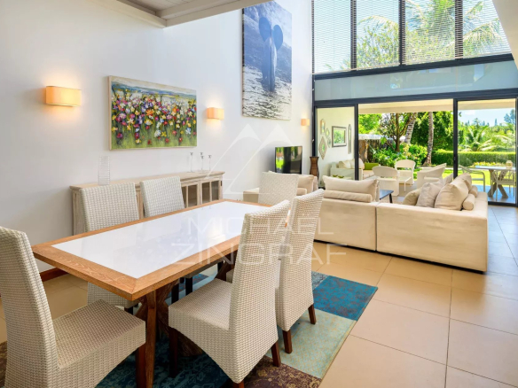 Open-plan living and dining area with a glass sliding door to a sunny outdoor garden.