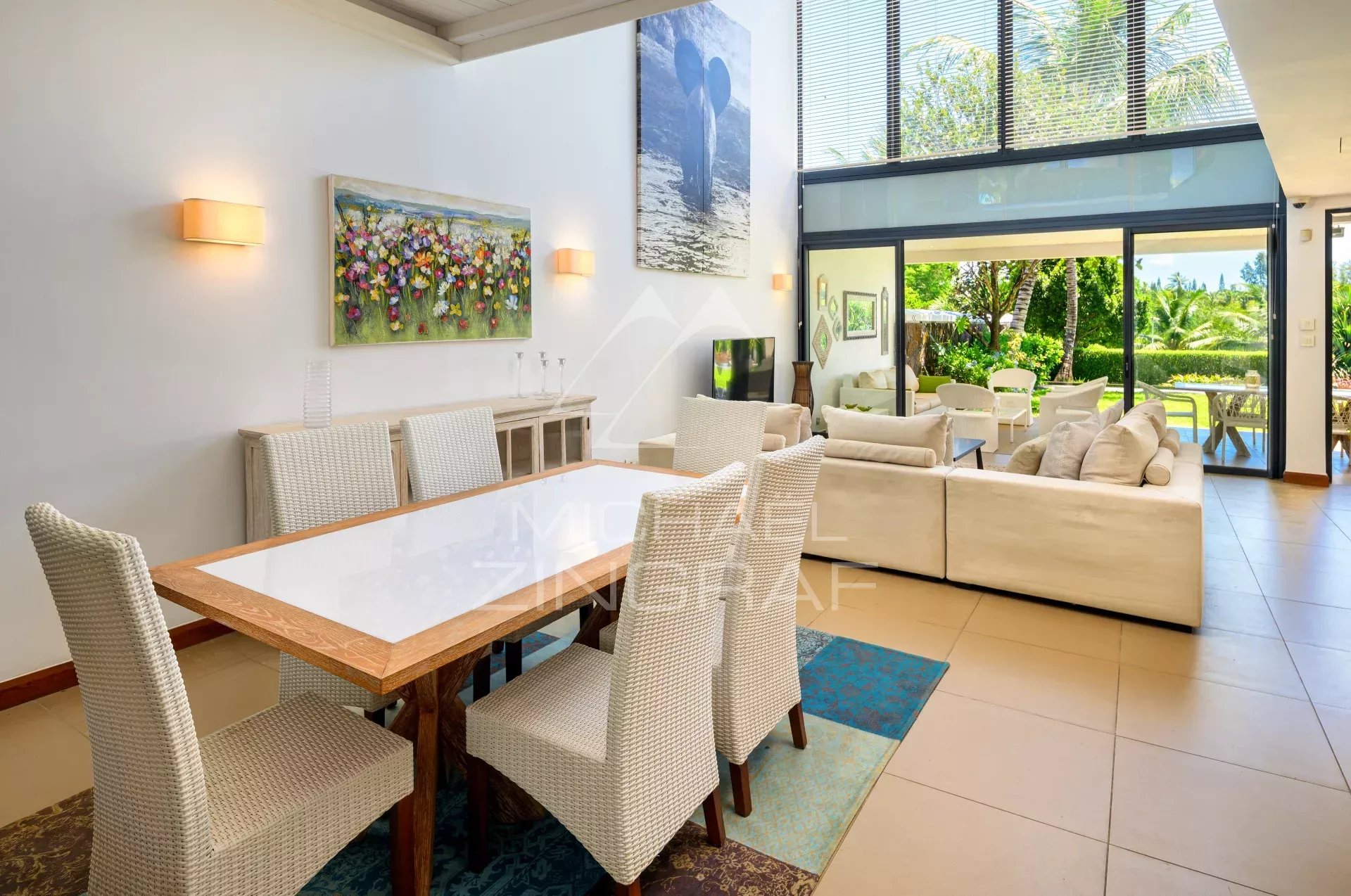 Open-plan living and dining area with a glass sliding door to a sunny outdoor garden.