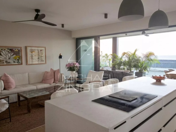 Intérieur d'un penthouse moderne avec cuisine ouverte et salon lumineux, vue sur la mer.