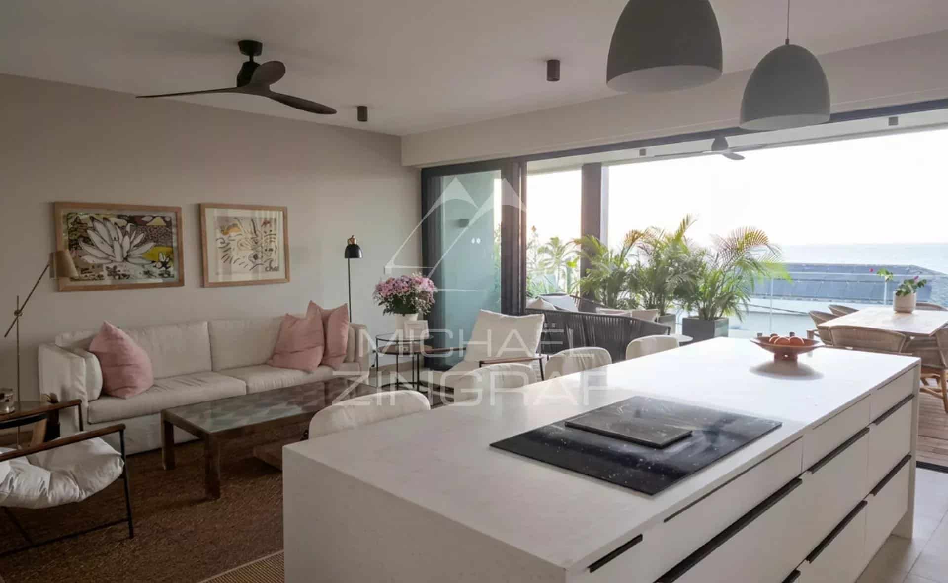 Intérieur d'un penthouse moderne avec cuisine ouverte et salon lumineux, vue sur la mer.
