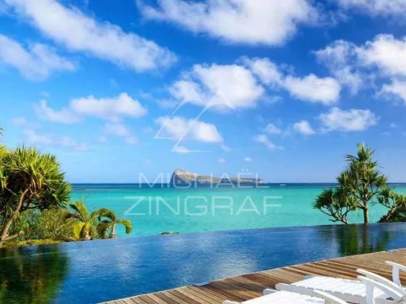 Vue sur la mer depuis un penthouse avec piscine à débordement et chaises longues.