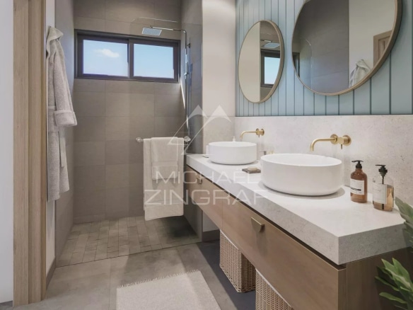Salle de bains moderne avec deux lavabos et douche, décorée de carreaux gris et de miroirs ronds.