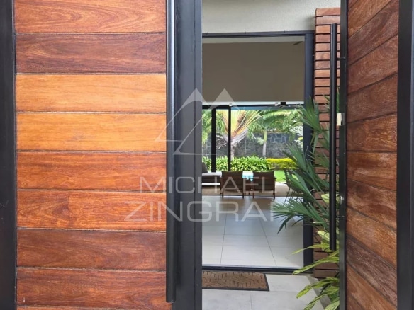 Entrance to a contemporary villa in Pereybère with wooden door and view into a bright interior space.